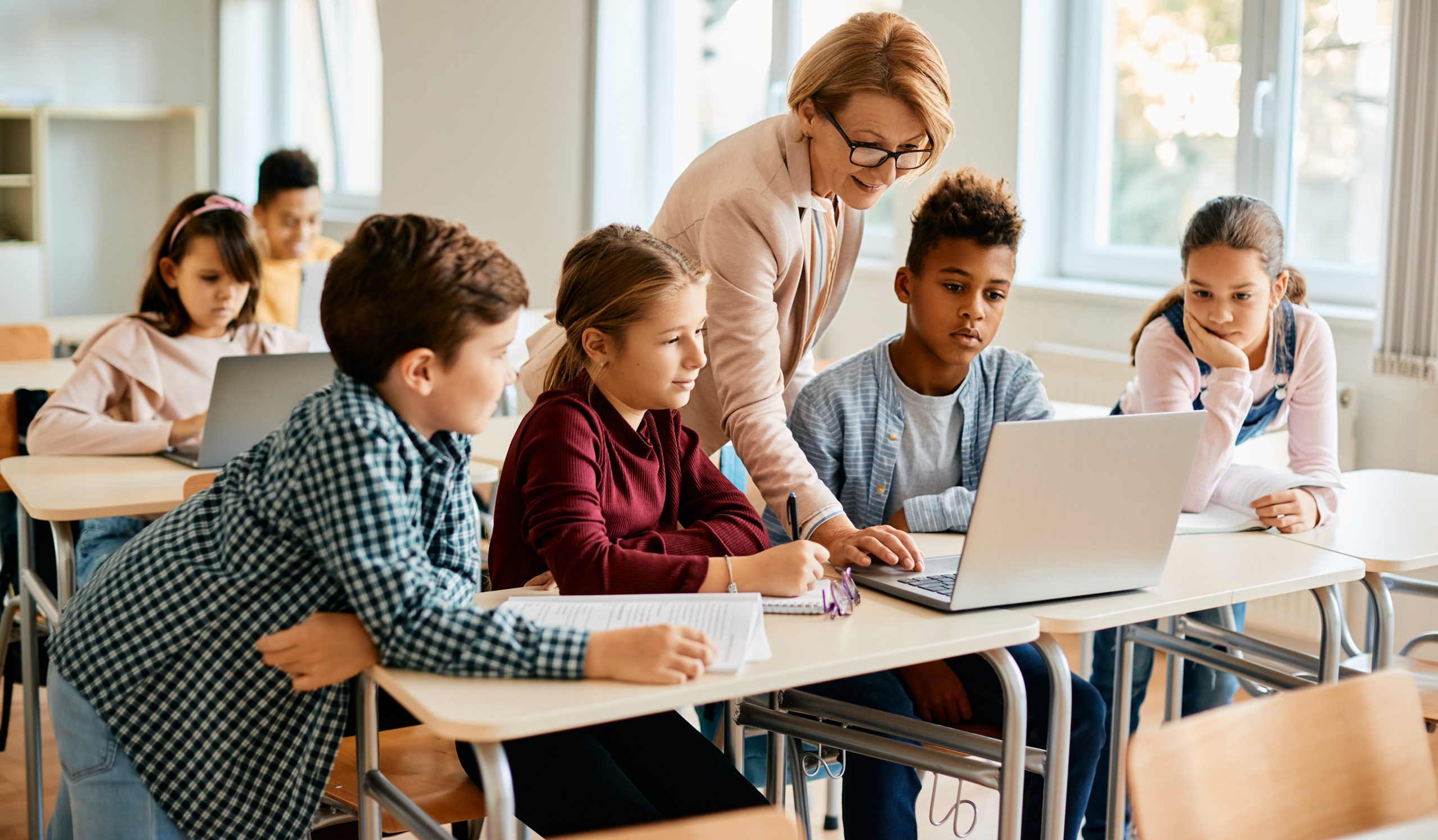group of elementary students having computer class with their teacher in the classroom.